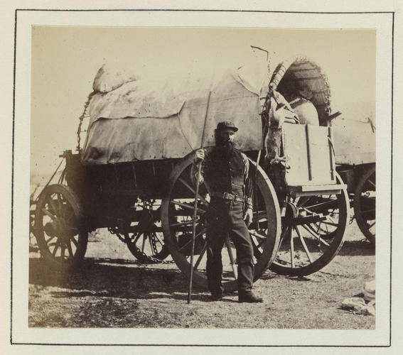 Man guarding a food supply waggon while encamped by a river in South Africa