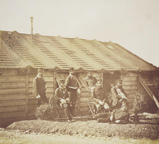Group outside a hut, with white dog