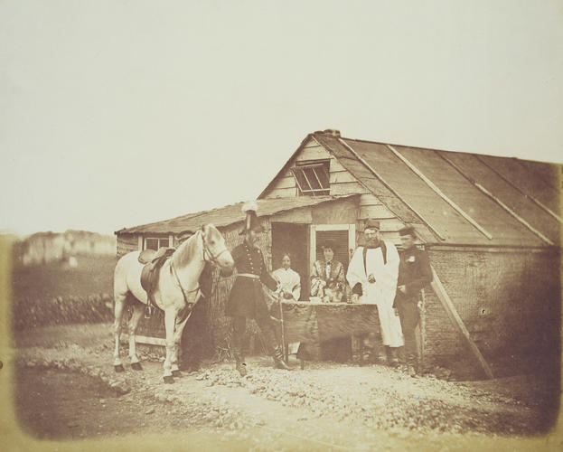 Group outside a hut, including two women and a Clergyman