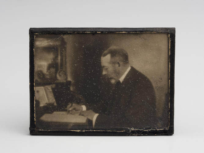 Miniature photograph of King George V at his desk, c. 1925. [Queen Mary's Doll's House]