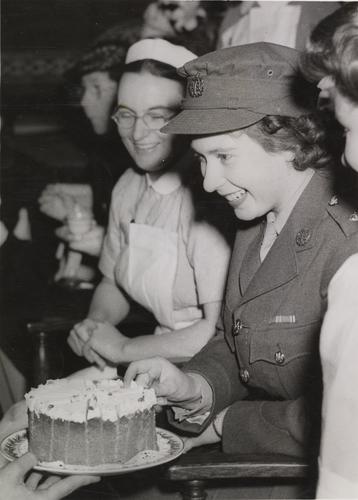 Princess Elizabeth accepting a piece of cake at a tea party at the Royal College of Nursing